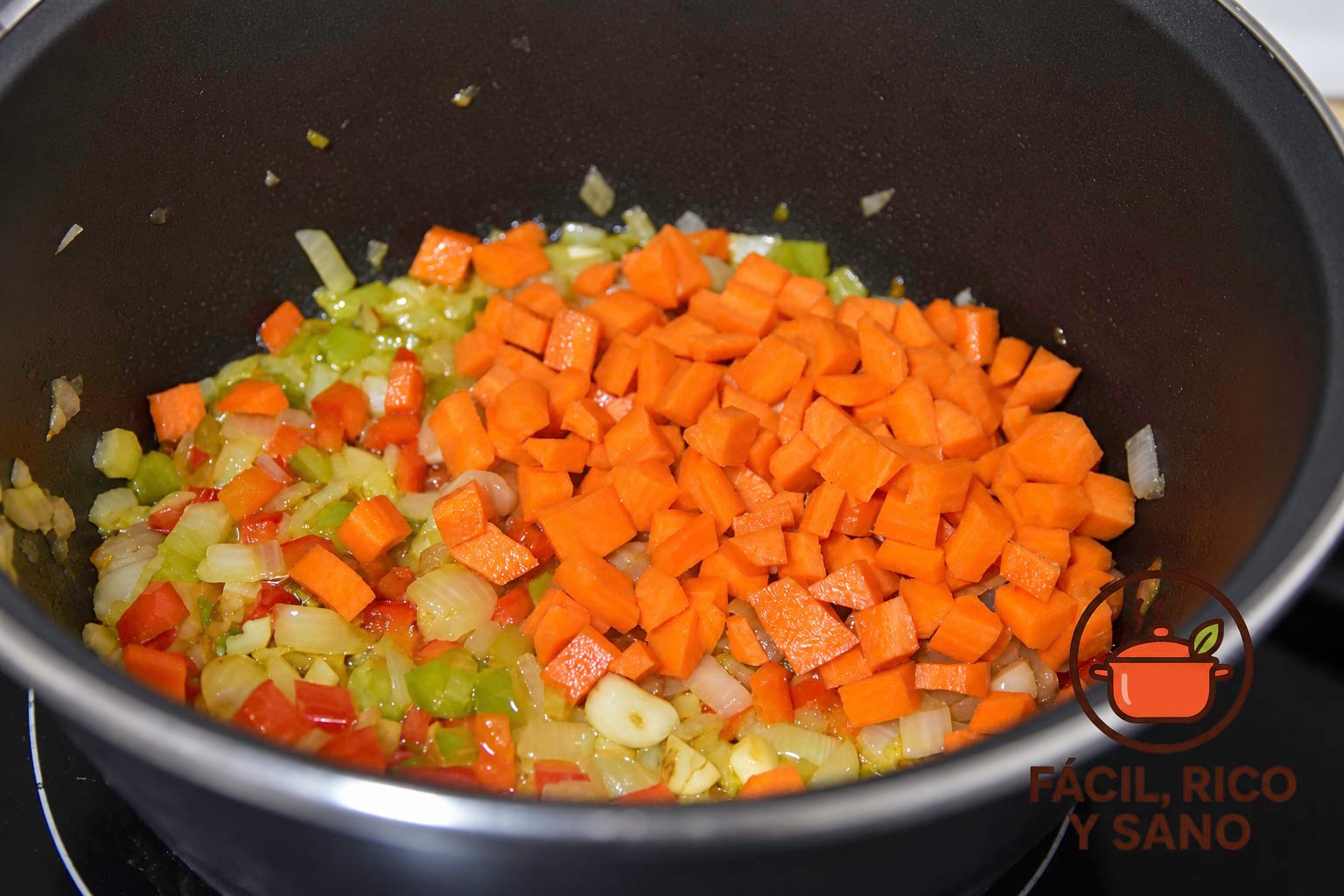 Zanahoria en dados y ajo añadidos al sofrito de cebolla y pimiento pochado