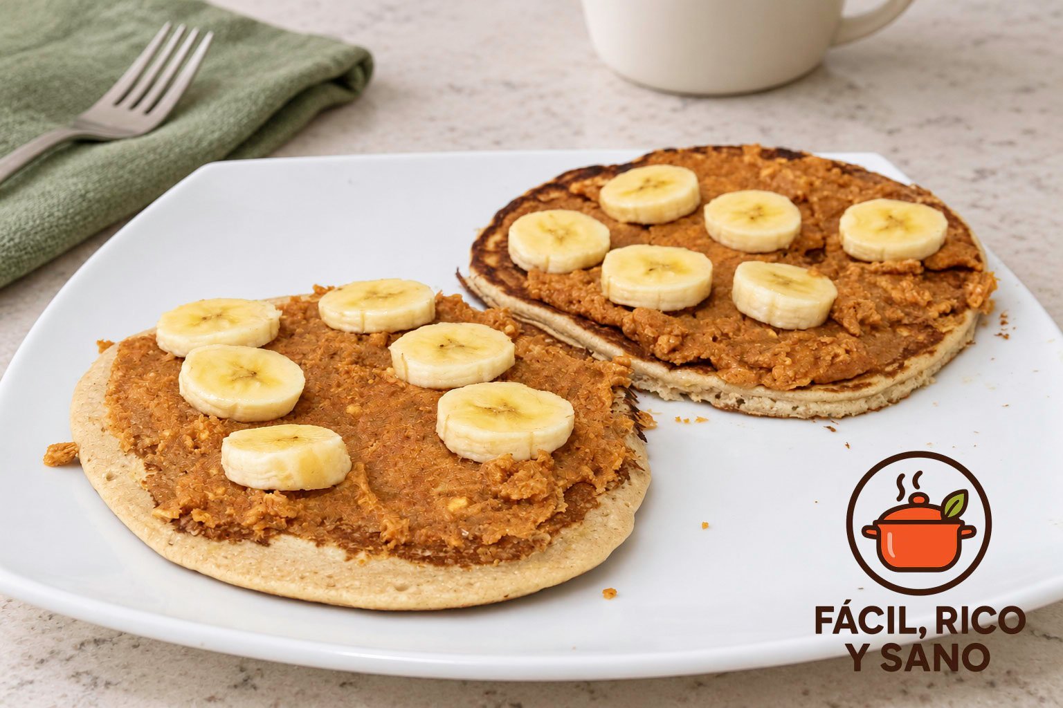 Dos tortitas de avena y plátano con crema de cacahuete y rodajas de plátano en un plato blanco