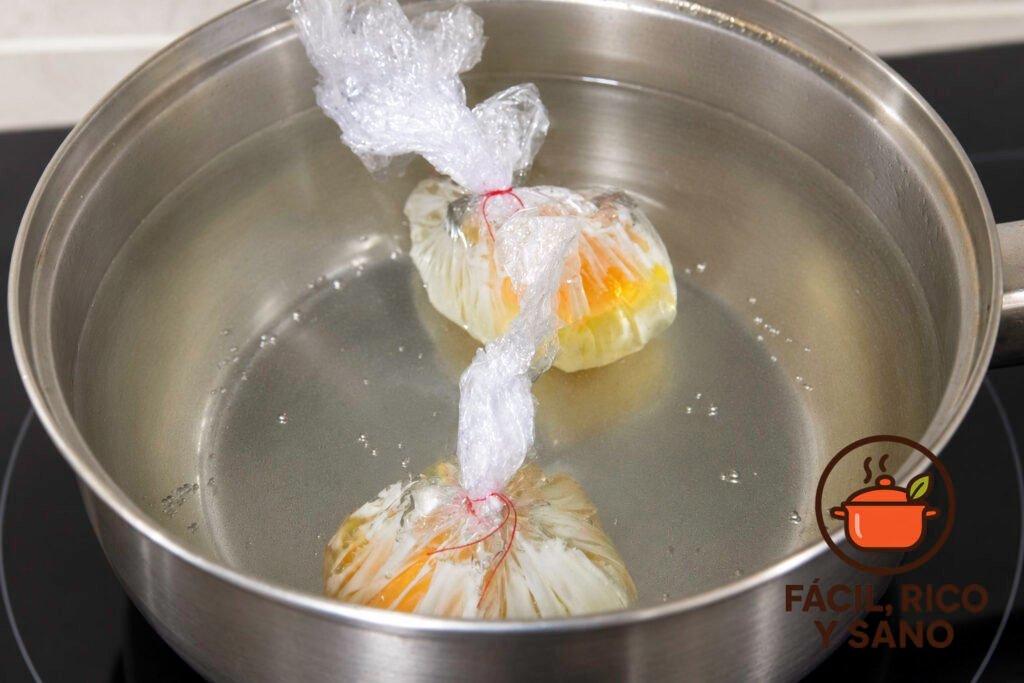 Dos huevos envueltos en film cociendo en un cazo con agua caliente sin llegar a hervir