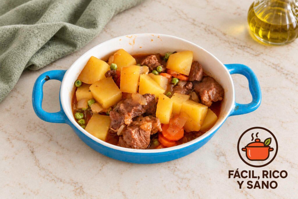 Estofado de ternera con patatas, zanahoria y guisantes en una cazuela azul