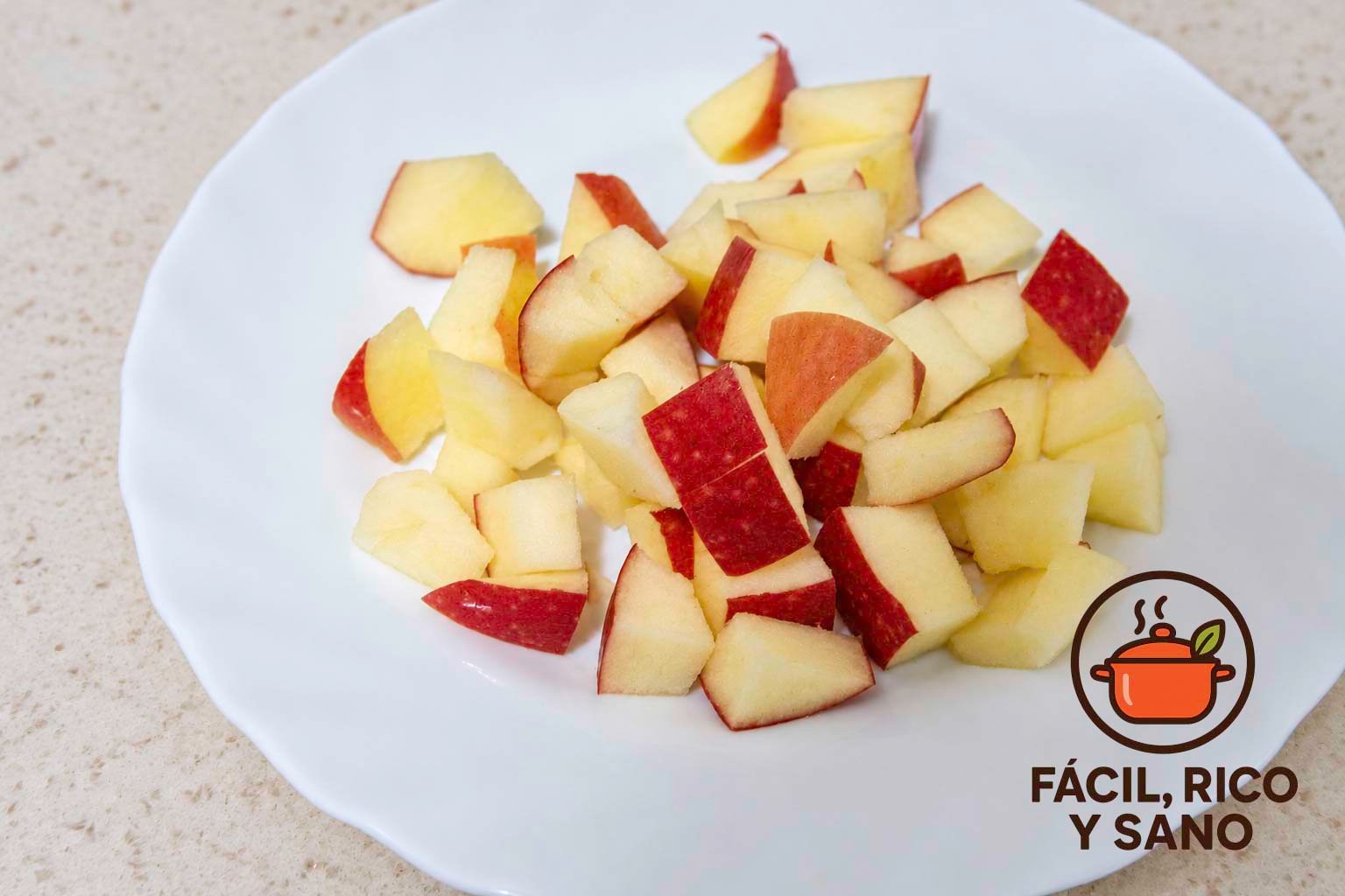 Manzana roja cortada en daditos en un plato blanco