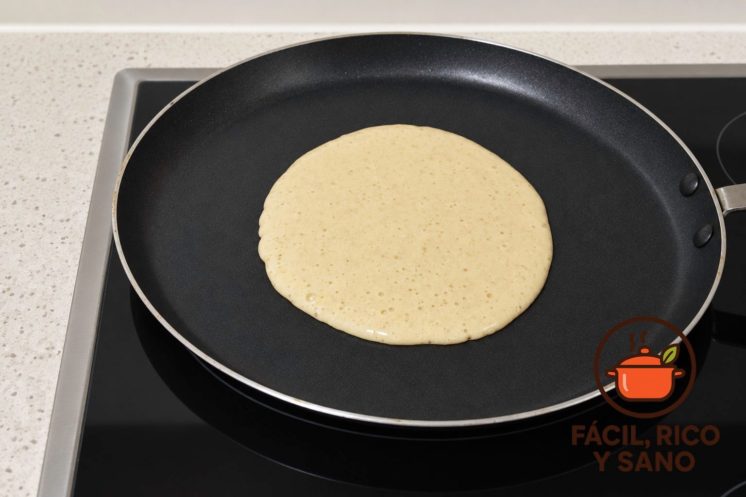 Masa de tortita de avena y plátano cuajándose en una sartén antiadherente sobre la vitrocerámica