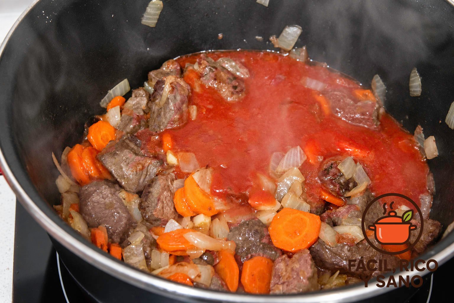 Tomate triturado añadido a la ternera con verduras en la cazuela