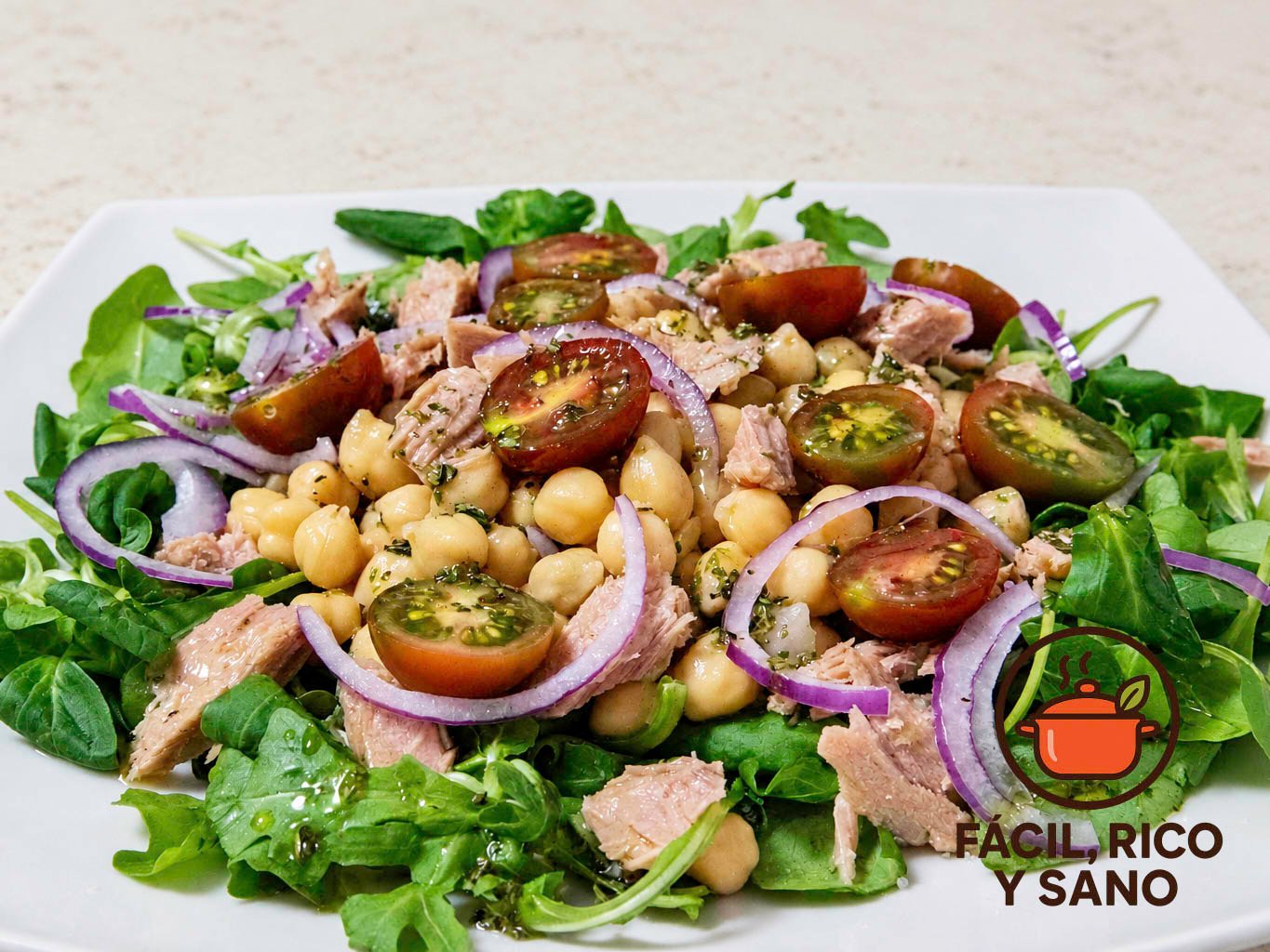 Ensalada de garbanzos con atún, tomates cherry y cebolla morada sobre canónigos y rúcula