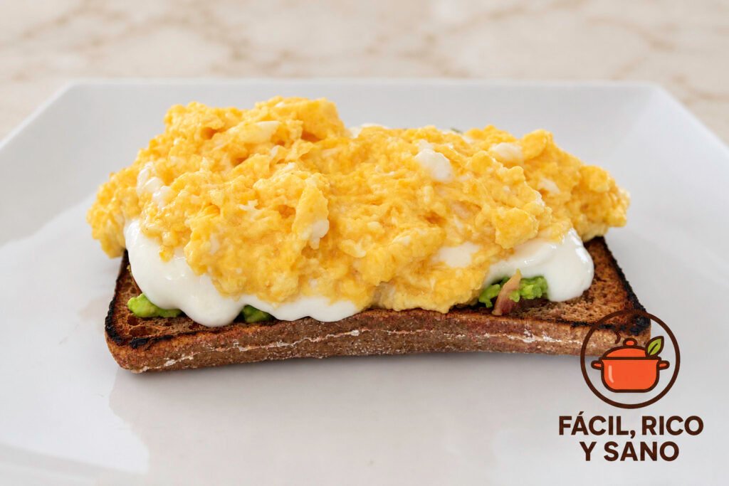 Tostada de pan integral con aguacate, queso fresco batido y huevo revuelto