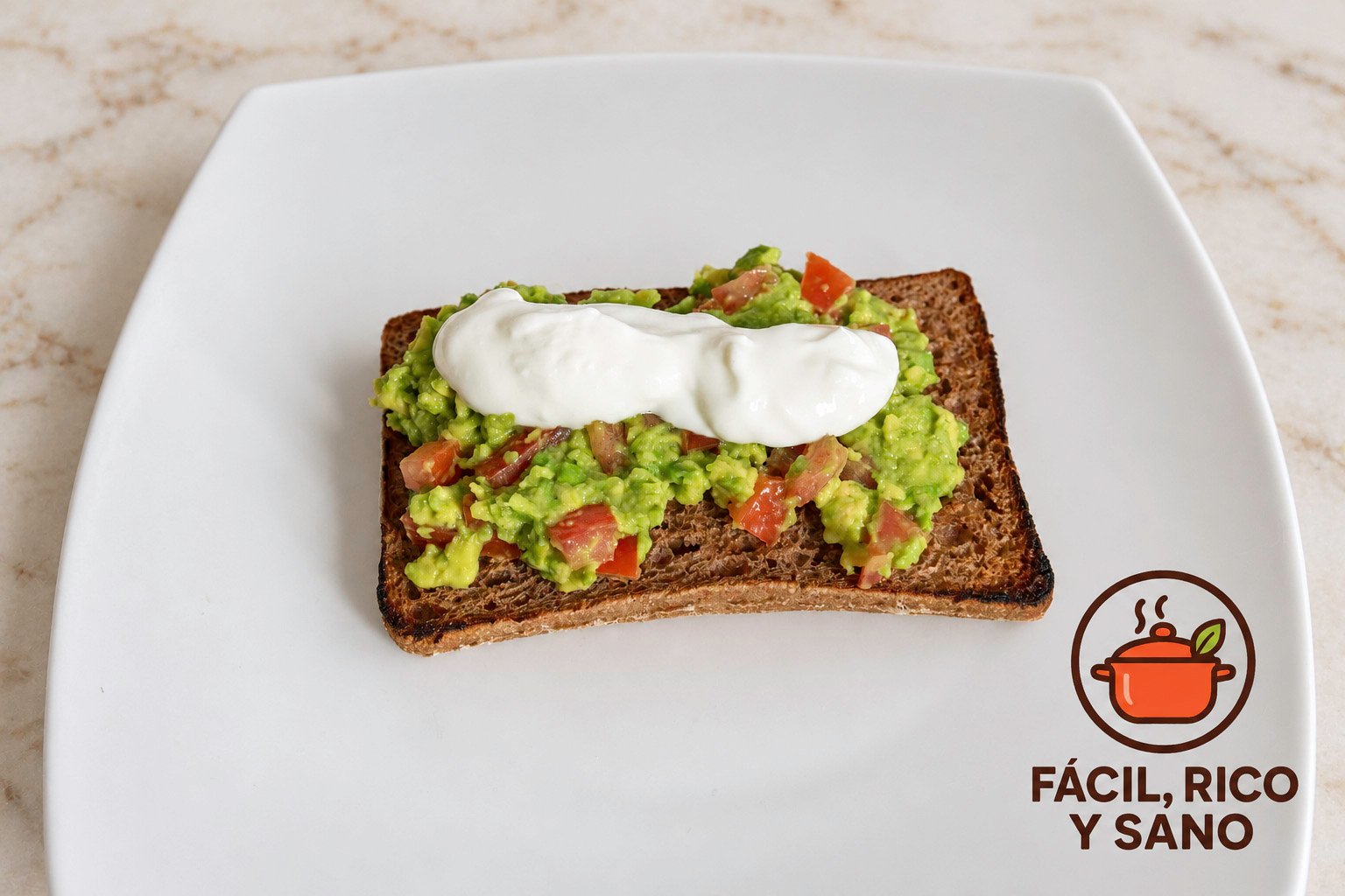 Pan integral tostado con aguacate machacado, tomate en dados y queso fresco batido antes de añadir el huevo